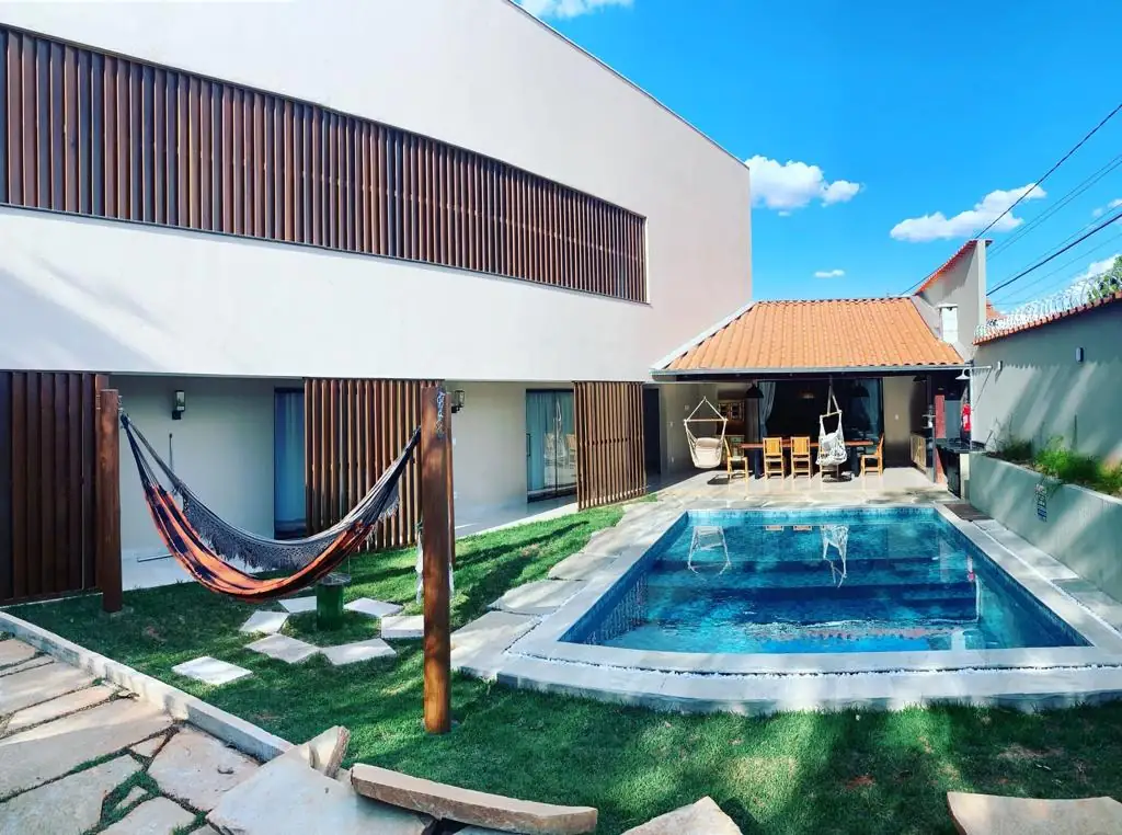 Piscina com área gourmet ao fundo, redes penduradas